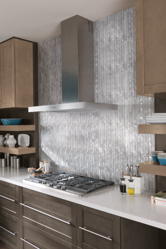 A close-up image of dark brown kitchen cabinets with a stainless steel backsplash and a stainless steel range hood.