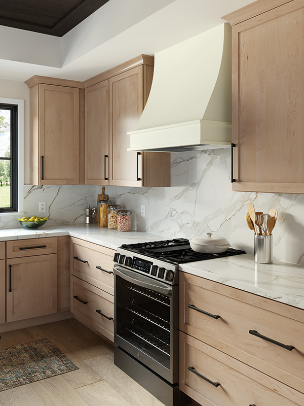 Marble kitchen counter with ample space, a modern black-colored oven, and light wood kitchen cabinets. 
