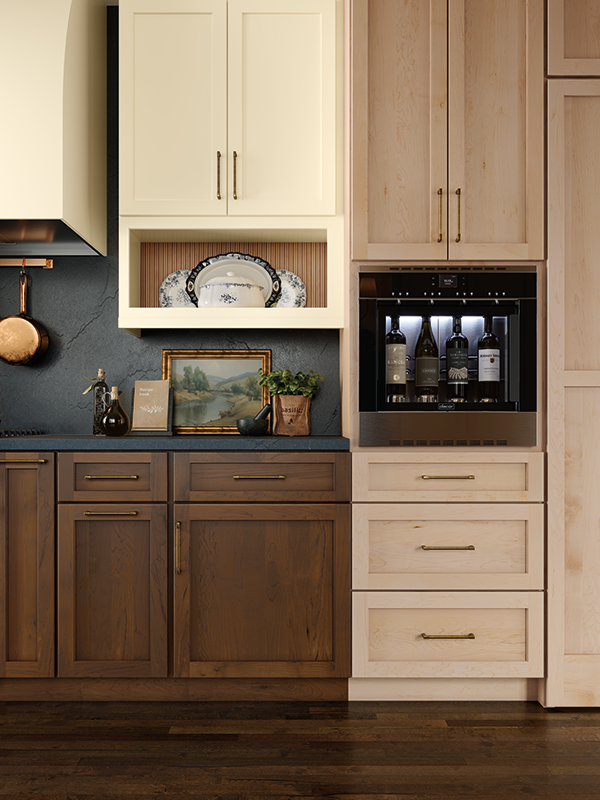 This close-up cabinet snapshot shows creamy-colored upper kitchen cabinets, a dark teal countertop and backsplash, and deep-toned wood-stained lower cabinets. 