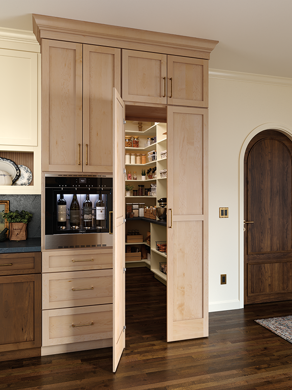 A walk-in kitchen pantry with sleek beverage station on the exterior, natural wood cabinets and door, with organized shelves inside. 