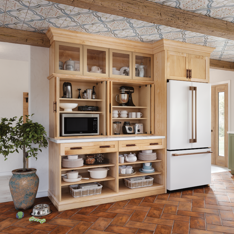 This section of the kitchen features a large wooden built-in with designated shelves and sections for appliances, bakeware, and servingware. The top shelf features glass doors, while the middle section is an open view of the appliances that usually rest behind wooden doors. On the right side of the installation is a white fridge to maintain an overall cohesive appearance in the kitchen. 