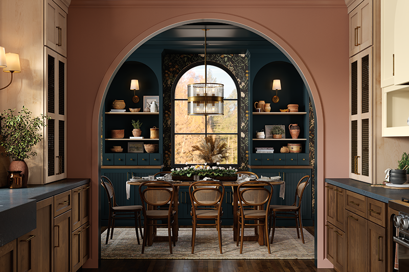 The view of a dining area from the kitchen, with deep turquoise paint, wallpaper, and a cozy wooden table with chairs. 
