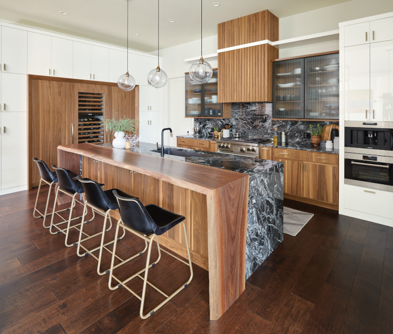 A kitchen with a mix of wood and stone for the cabinets, island, and backsplash.