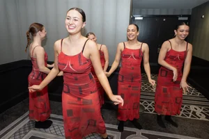5 women dressed in red smiling and laughing together.