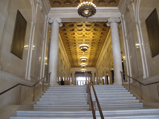 The inside of an empty building with a staircase that leads up to a hallway.