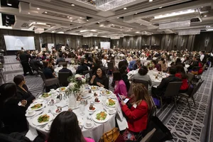 Event photo with everyone sitting at tables and food in front of them.