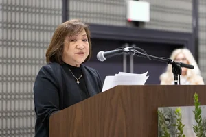 Woman in black speaking at a podium.