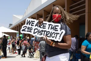 Holding up a "WE ARE THE 2nd DISTRICT!" sign
