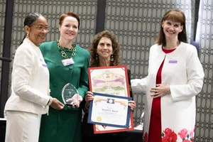 4 women posing on stage with awards.