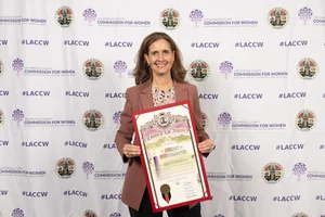 A woman smiling for a photo while holding up an award.