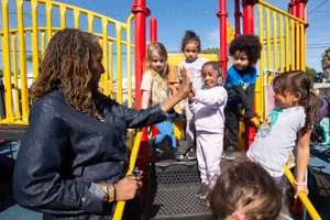 Supervisor Mitchell high fiving young girl on a playground
