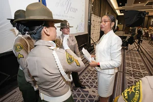 County officers speaking with a woman in front of a projector screen.