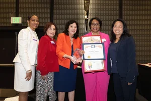 a group of women smiling and holding up a few awards.