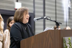 Woman in black speaking at a podium.