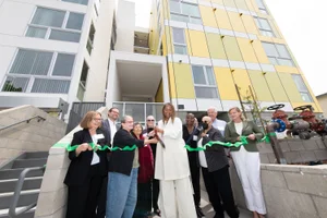 Supervisor Mitchell cutting a ribbon in front of two buildings