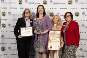 4 women smiling and holding up a few awards.
