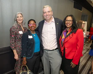 3 women and 1 man posing for a photo together.