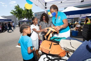 Supervisor Mitchell handing out a backpack at the LA Care Back to School Giveaway