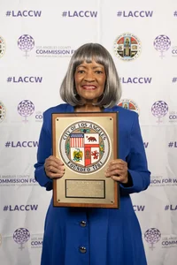 A woman smiling and holding up an award.