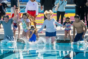 Supervisor Hahn jumping into a pool with a young group of children