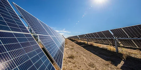 Solar panels in a dirt field.