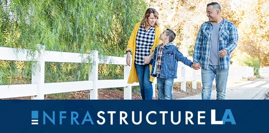 Mom and Dad walking down the sidewalk with their kid.