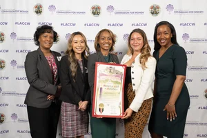 5 women smiling for a photo while holding up an award.