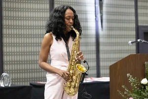 Woman in pink playing a trumpet on stage.