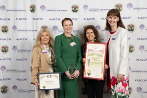 4 women smiling while holding up a few awards.