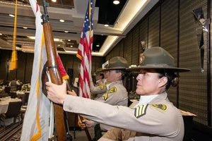 Military soldiers holding a rifle and flags.