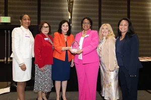 A group of women smiling and holding up an award.