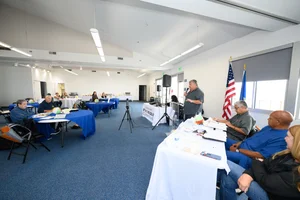 A group of people sitting at tables at an event where a man is speaking at the podium,