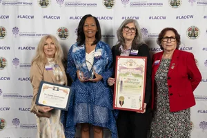 4 women smiling and holding up a few awards.