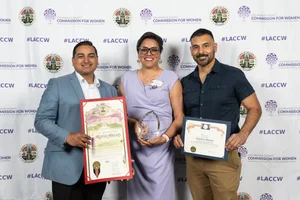 3 people posing for a group photo while they each hold up an award.