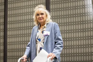 a woman smiling and holding a piece of paper.