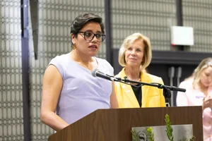 Woman in purple speaking at a podium.