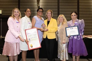 a group of women holding up a few awards.