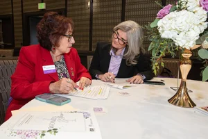 2 women sitting at a table discussing paperwork.