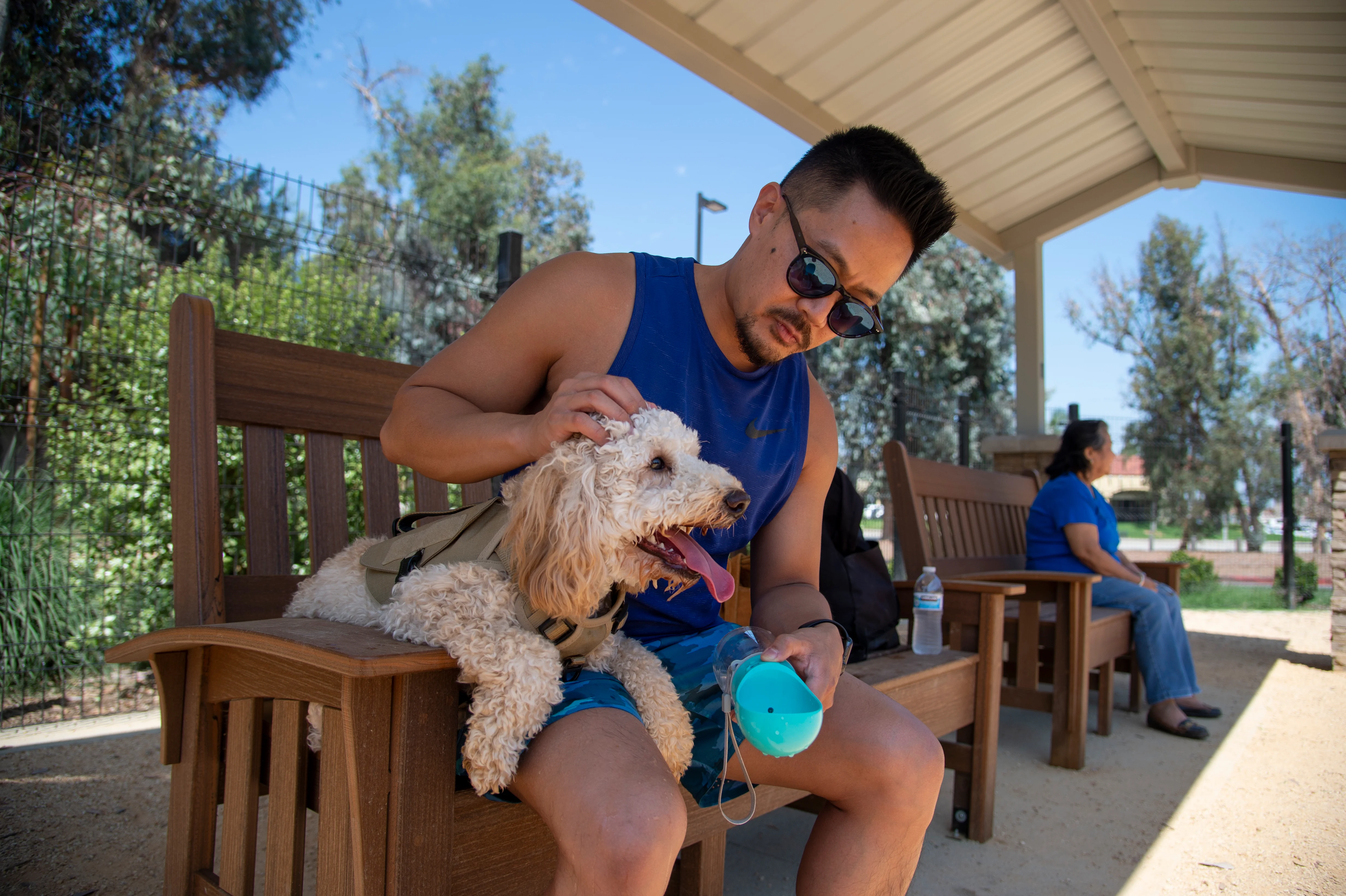 A man sitting at a bench petting his dog