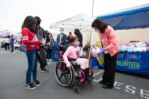 Supervisor Solis handing out stuffed animal at the DPSS Backpack Giveaway