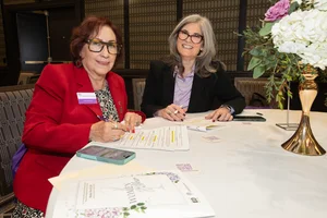 2 women sitting at a table posing for a picture.