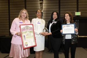 a group of women holding up a few awards.