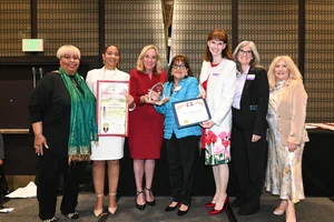 a group of women holding up a few awards.