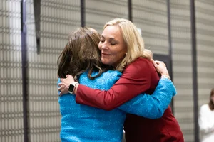 Supervisor Barger hugging someone at a podium.