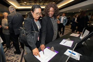 2 people looking and pointing at a document on a table together.