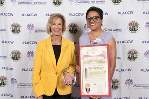 Supervisor Hahn smiling for a photo with another woman while they both hold up awards.