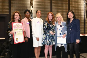 A group of women smiling and holding up a few awards.