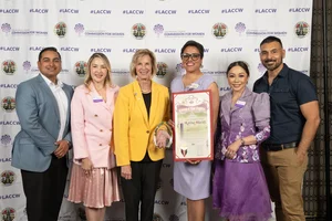 Supervisor Hahn smiling for a group photo while they hold up a couple of awards.