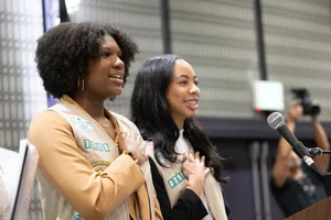 2 women holding their hands to their hearts.