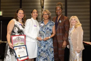a group of women smiling and holding up a few awards.